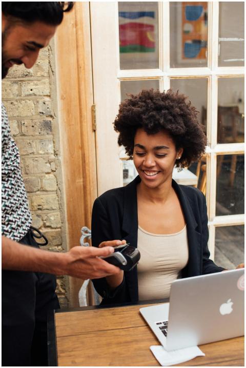 A smiling woman uses a pay terminal at her work de