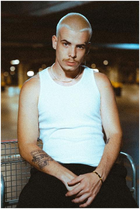 Portrait of a young man with tattoos wearing a tan