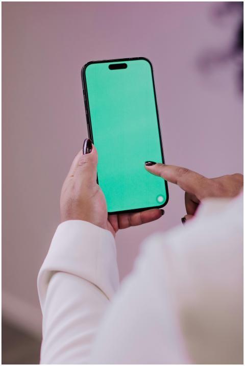 Person using a smartphone with a green screen for