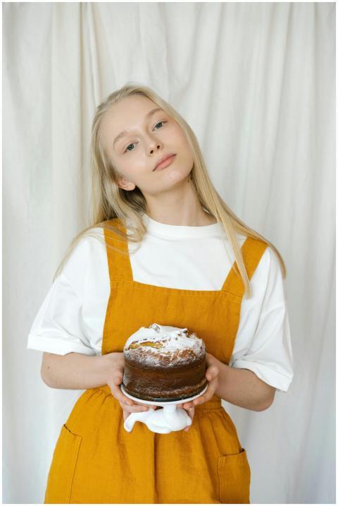 Young girl in a yellow apron holding a homemade ca