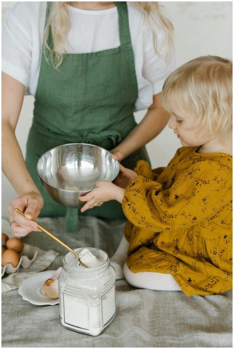 High angle of little daughter sitting on table wit