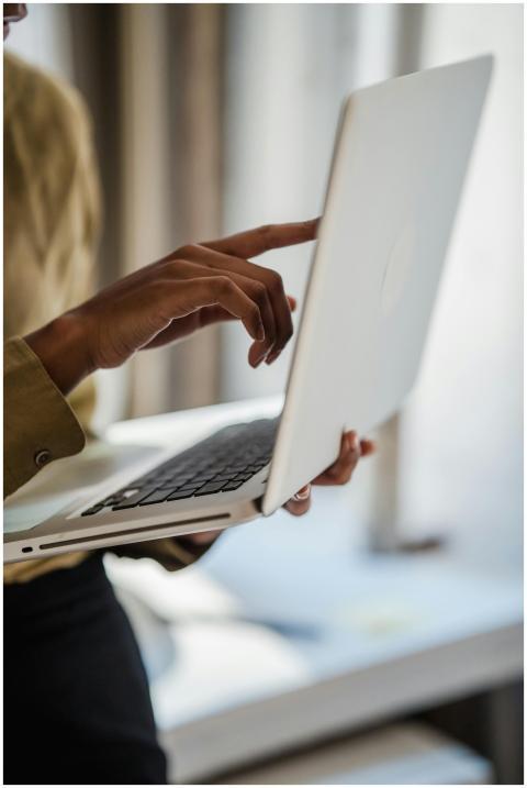 A woman uses a laptop indoors, captured in a verti