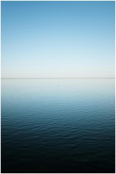 A serene view of a calm blue ocean under a clear s