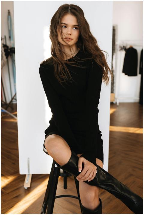 Stylish young woman in a black dress and boots pos