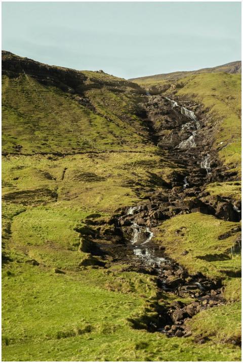 A serene waterfall cascades through a verdant vall