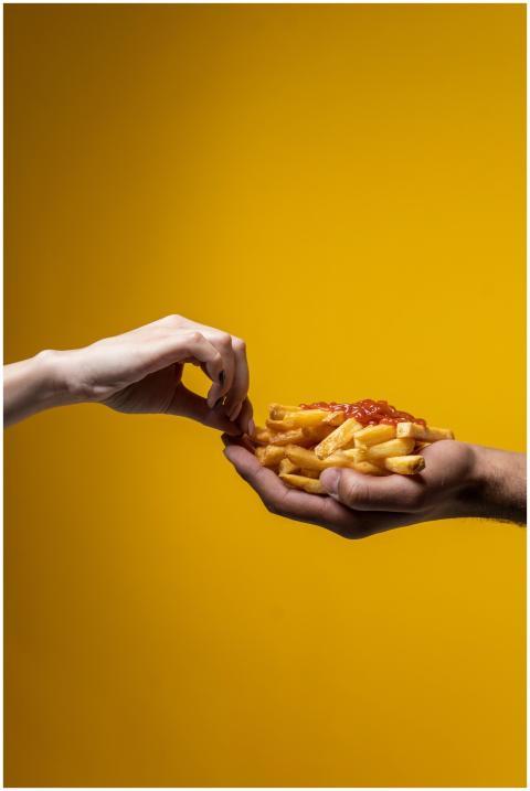 Close-up of hands sharing french fries against a v