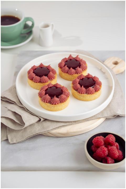 Fresh raspberry tarts with cream topping served on