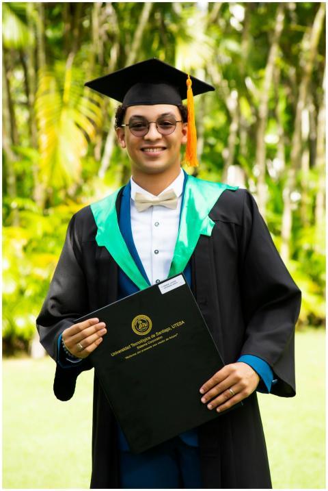 Young adult in graduation attire holding a diploma