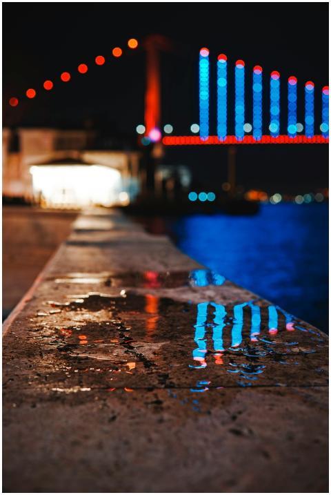 Vibrant lights of a bridge reflecting on water at