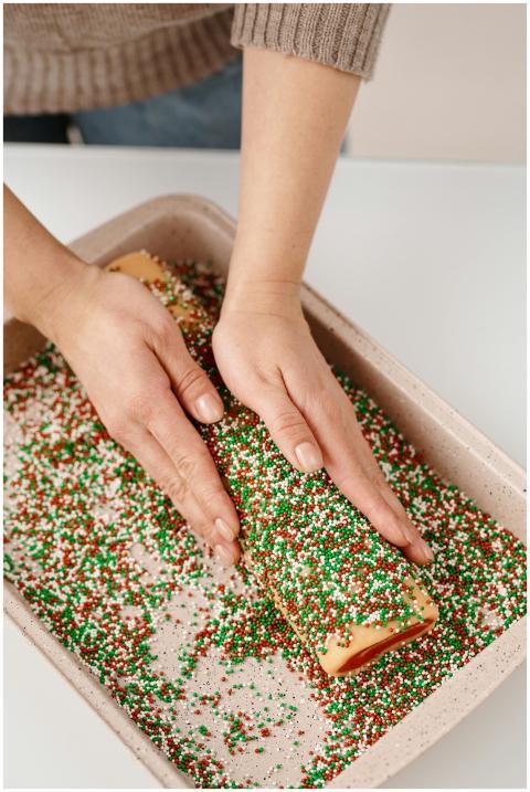 A person decorating a Christmas roll with colorful