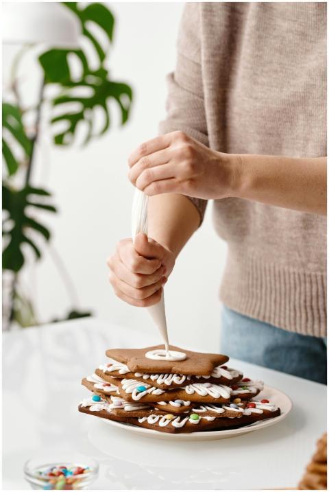 Close-up of hands icing a stack of homemade Christ