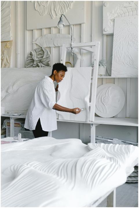 A woman artist meticulously works on an abstract s
