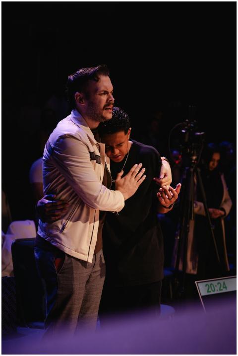 Two men share an emotional embrace during a worshi