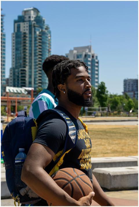 Athletic man with basketball outdoors, sunny urban
