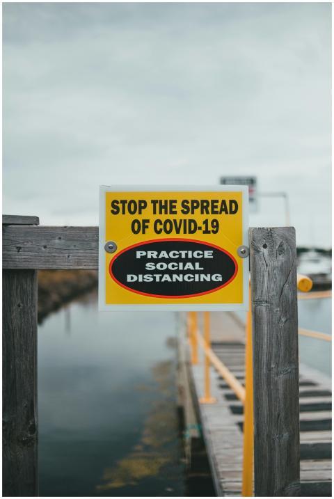 Yellow sign urging COVID-19 social distancing on a