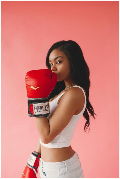 Stylish woman posing with red boxing gloves on a p