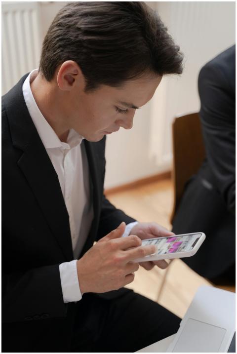 Professional in a black suit using a smartphone in