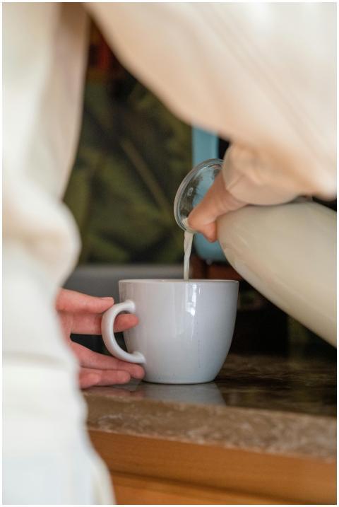 Close-up of milk being poured into a white cup on