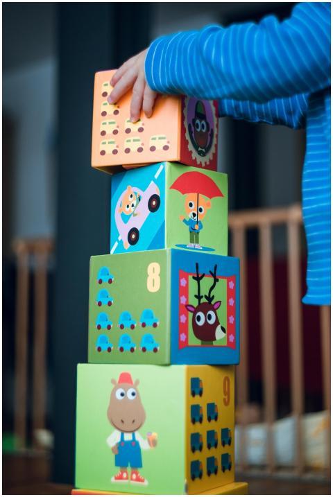 A child playing indoors, stacking colorful wooden