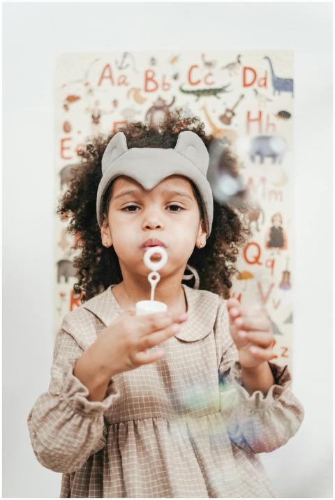 African child in a cute dress blowing bubbles indo