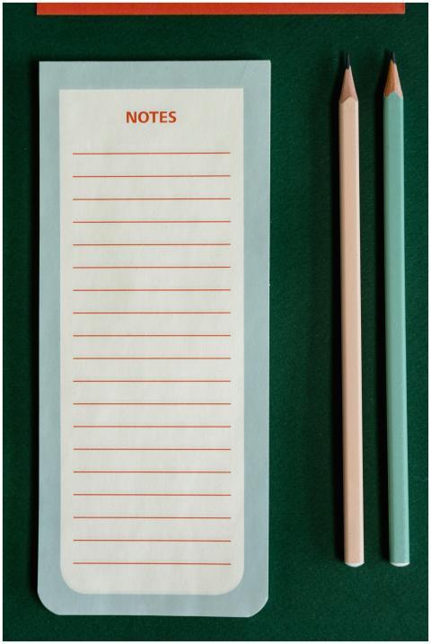 Minimalist notepad and pencils arrangement on a gr
