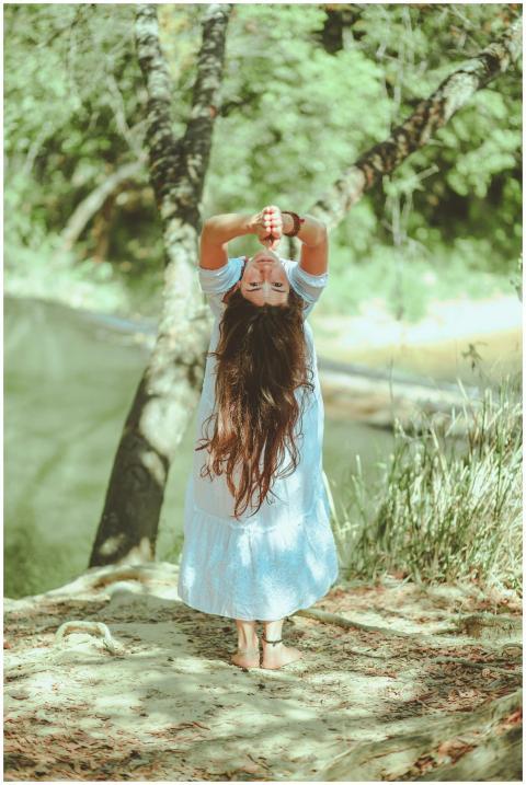 A woman performs a yoga pose by a tranquil lakesid