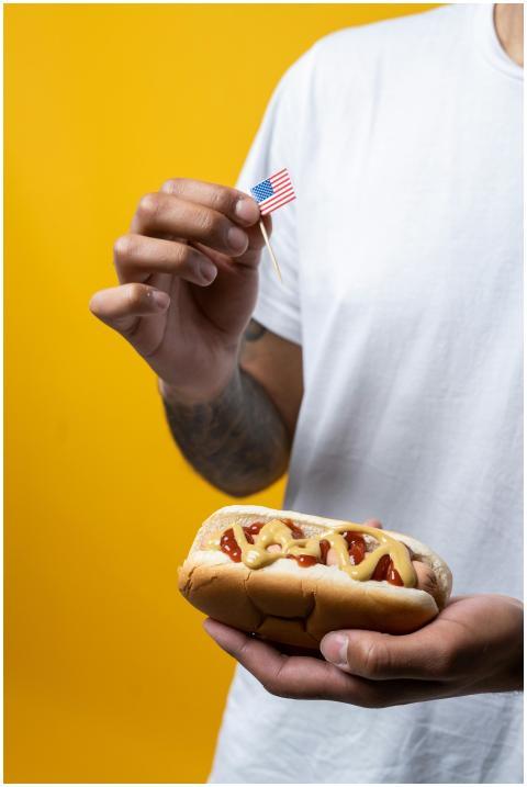 A person holding a classic hot dog with mustard an