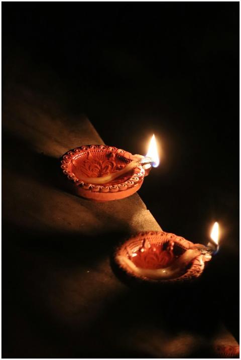 Clay diyas with flickering flames symbolizing Diwa