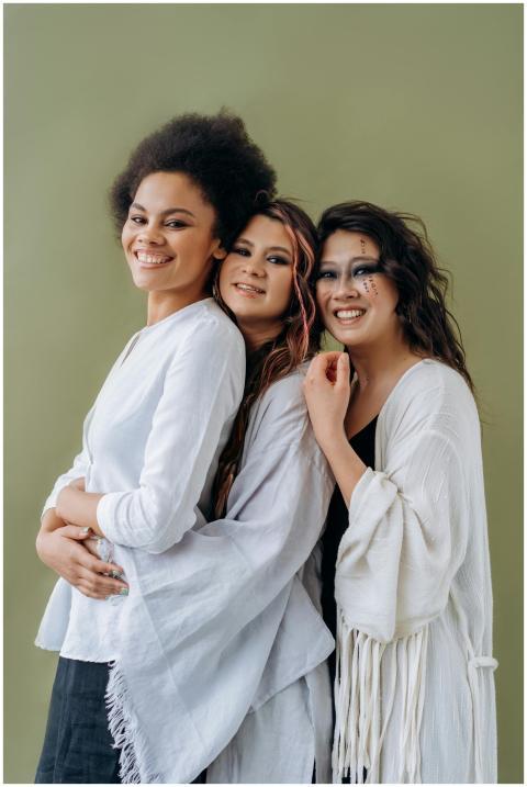 Three multicultural women in white attire stand ha