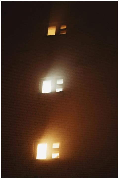 Moody shot of illuminated windows in a foggy build
