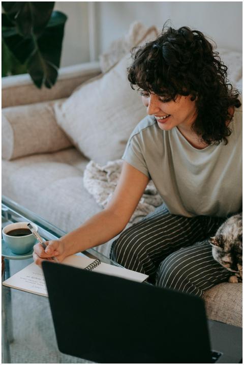 Smiling woman studying with a notebook and laptop