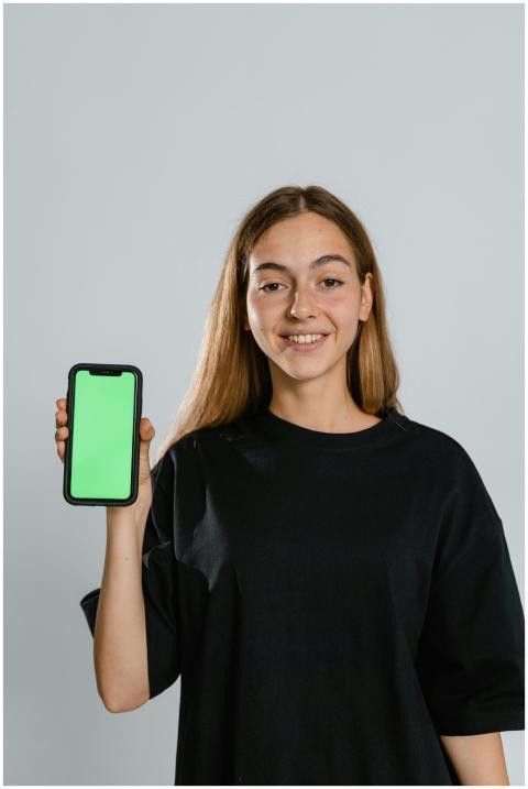 Smiling teenager in black t-shirt holding smartpho