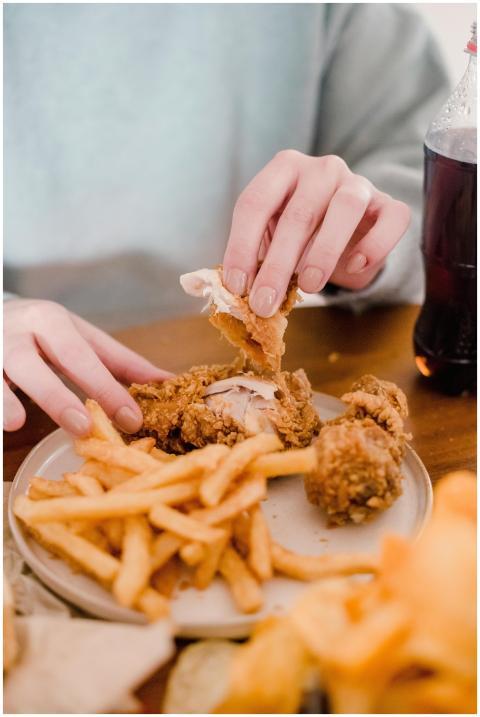 Crop anonymous female eating fried chicken in brea