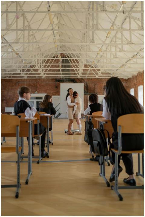 A teacher comforts a student in a bright classroom