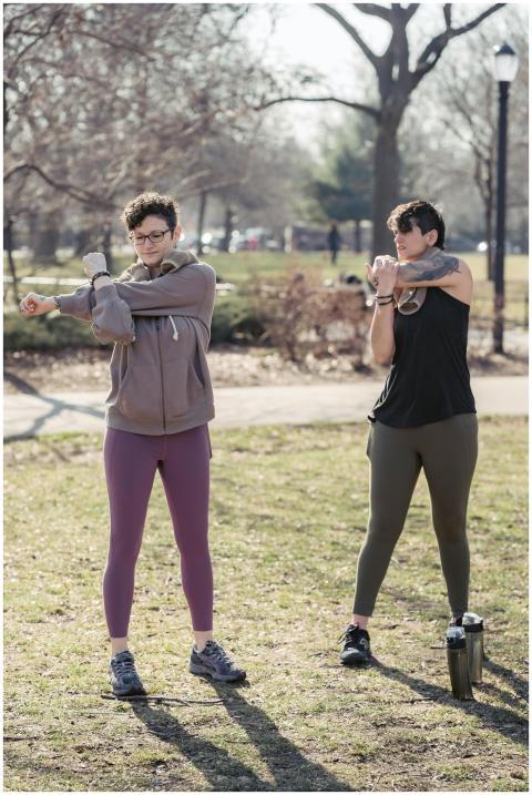 Two women stretching and exercising outdoors in a