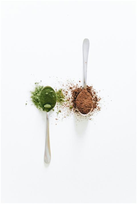 Top view of two teaspoons with green matcha and br
