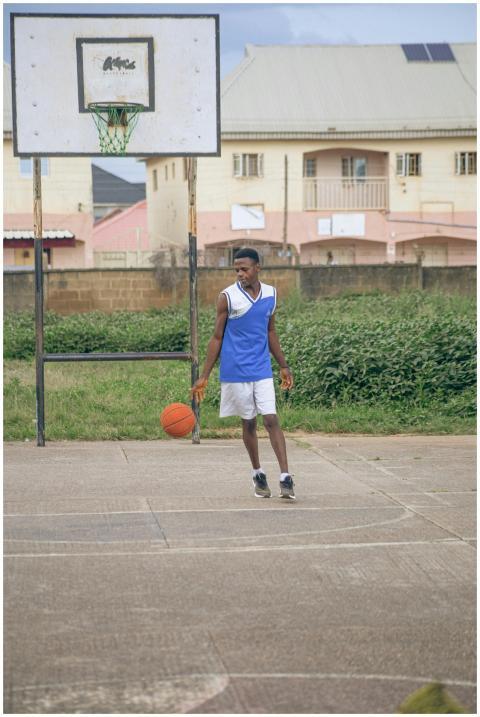 A young man dribbles a basketball on an outdoor co