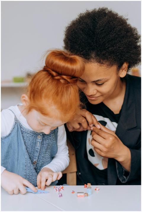 A teacher helps a child with an educational craft