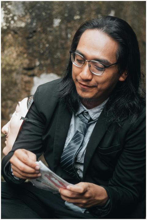 Asian man in business attire holding a mask in a c