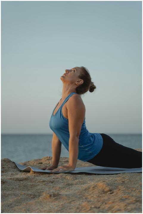 Caucasian woman performing yoga pose on mat by the