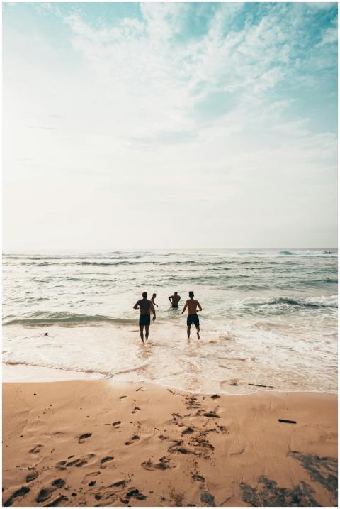 Three friends run into the ocean on a sunny day at