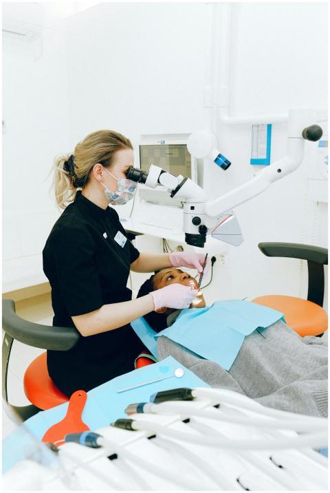 Female dentist in clinic examining a patient with