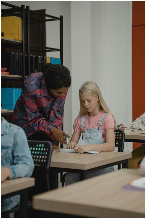 A teacher assisting a student in a classroom, fost