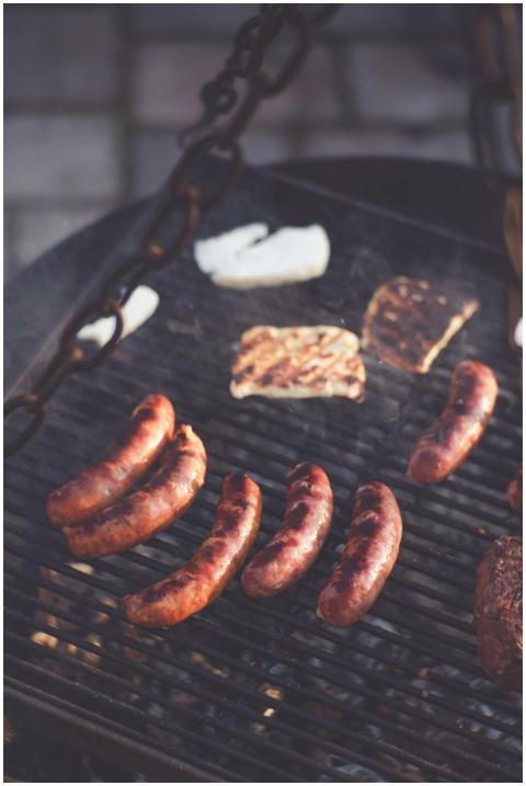 Delicious sausages and steak grilling over an outd