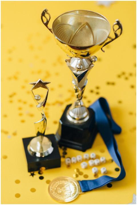 Golden trophies and medal displayed on a confetti-