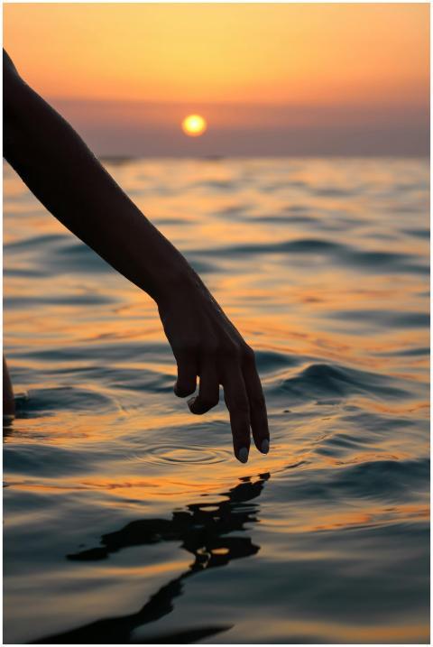 A tranquil moment with a hand touching the ocean w