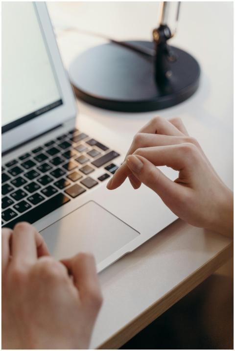 Close-up of hands using a laptop's touchpad in an