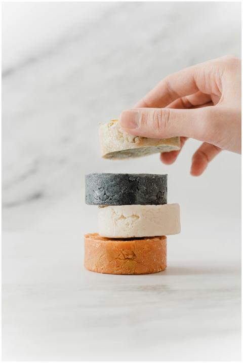 A hand placing eco-friendly soap bars in a stack,