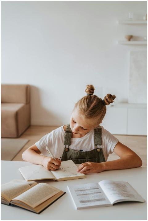 A young girl sits at a table indoors, engaged in w