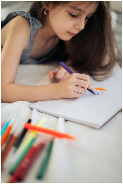 A young girl concentrates on drawing with colored